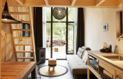 Moderne tiny house i Maasduinen, Holland, med trægulve, loft, sofa, spiseområde og store vinduer.