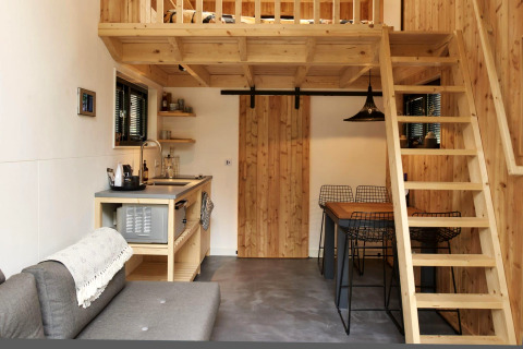 Interieur van een tiny house bij Maasduinen, Nederland, met vide, kleine keuken en eethoek.