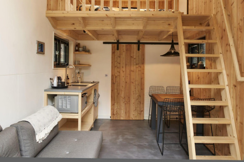 Interieur van een tiny house in Maasduinen, Nederland, met houten loft, compacte keuken en eettafel.