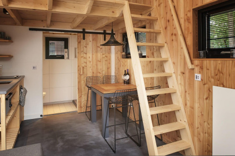 Interno di Tiny House at Maasduinen nei Paesi Bassi con pareti in legno, scala e zona pranzo.