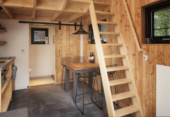 Interiør af Tiny House at Maasduinen i Holland med trævægge, trappe, spisestue og lille køkken.