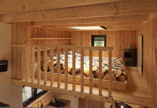 Altillo para dormir en la Tiny House de Maasduinen, Países Bajos, con paredes de madera y tragaluz