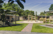 Buitenaanzicht van 6x bungalette lodge op Vakantiepark Mölke in Nederland, met speeltuin en groene omgeving.