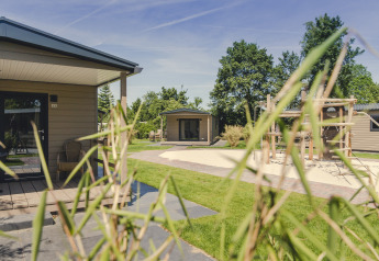 Vista exterior de 6x bungalette en Holiday Park Mölke, Países Bajos, con zona de juegos y bonita vegetación.