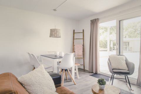 Licht interieur van een lodge met moderne meubels en grote ramen bij 6x bungalette, Holiday Park Mölke.