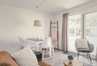 Licht interieur van een lodge met moderne meubels en grote ramen bij 6x bungalette, Holiday Park Mölke.