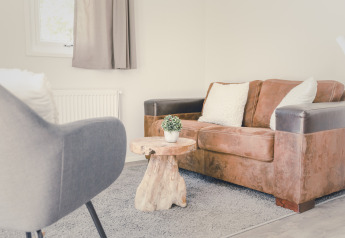 Wohnbereich in einem 6x Bungalette im Holiday Park Mölke Niederlande mit braunem Sofa und Holztisch.