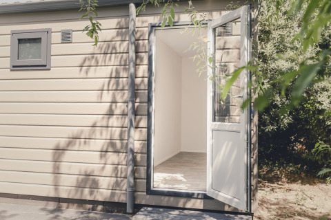 Exterior view of an open door leading into a bright, modern 6x bungalette at Holiday Park Mölke, Netherlands.
