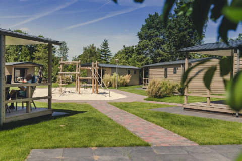 Feriebungalower med legeområde omgivet af grønne træer og græs på Holiday Park Mölke, Holland.