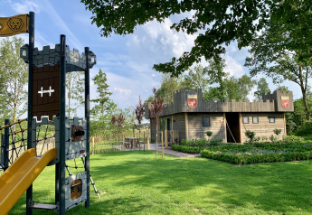 Spielplatz und hölzerne Lodge im Burgenstil im Holiday Park 't Rheezerwold in den Niederlanden.