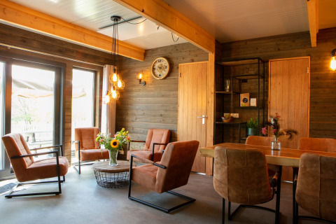 Interior de lodge en Castle the Pond Gate en Holiday Park 't Rheezerwold, Países Bajos, con sillas y madera.