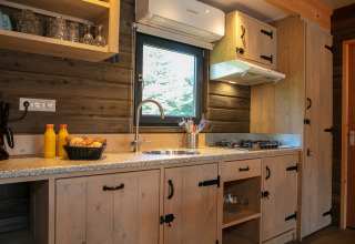 Modern lodge kitchen at Castle the Pond Gate, Holiday Park 't Rheezerwold, Netherlands with wood cabinets.