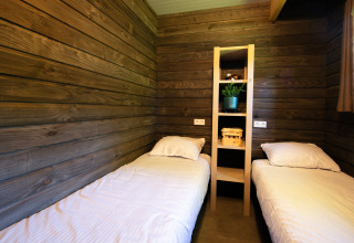 Dos camas individuales en una habitación de madera en Castle the Pond Gate, Holiday Park 't Rheezerwold, Países Bajos.