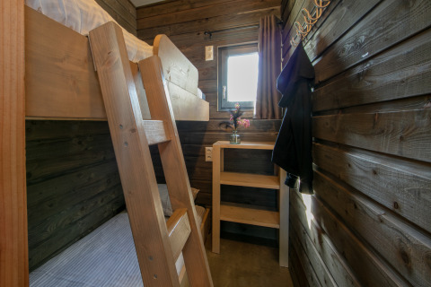 Cozy lodge room at Castle the Pond Gate with bunk bed, wooden walls, desk, and small window.