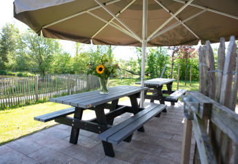 Udendørs picnicbord med blomster under en parasol ved Castle the Pond Gate, Holiday Park 't Rheezerwold.