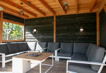 Überdachte Terrasse mit Holzdach, schwarzer Wand, gemütlicher Grausofa und Holztisch im Castle the Pond Gate.
