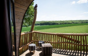 Udsigt fra Treelodge tiny house på Gulperberg i Holland med træterrasse og grønne marker i baggrunden.