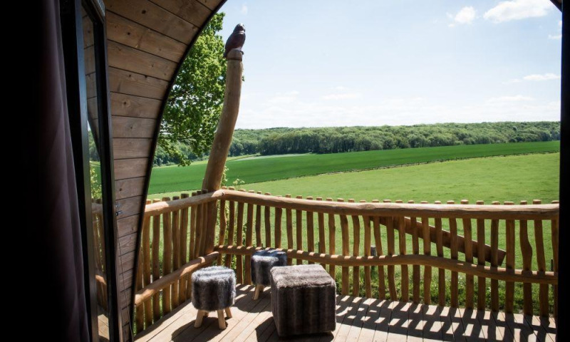 Vista desde la tiny house Treelodge en Gulperberg, Países Bajos, con terraza de madera y campos verdes.