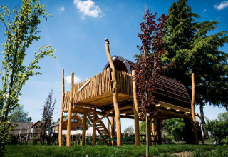 Casa pequeña llamada Treelodge elevada sobre pilotes de madera, rodeada de árboles en Gulperberg, Países Bajos.