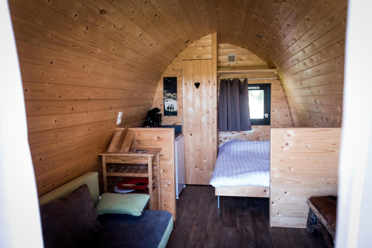 Vista interior de la casa pequeña Treelodge en Gulperberg, Países Bajos, con cama y paredes de madera.