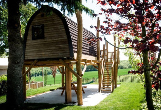 Tiny house Treelodge op palen bij Gulperberg in Nederland, omringd door bomen en een groene tuin.