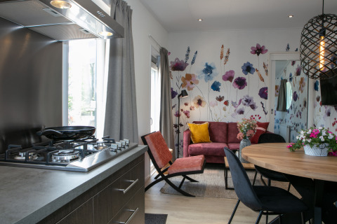 Cocina y sala modernas de tiny house con mural floral en Forest Lodge, Holiday Park 't Rheezerwold, Países Bajos.