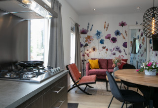 Cocina y sala modernas de tiny house con mural floral en Forest Lodge, Holiday Park 't Rheezerwold, Países Bajos.
