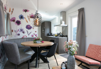 Moderne tiny house Forest Lodge på Holiday Park 't Rheezerwold, hyggelig stue og køkken med blomstervæg.