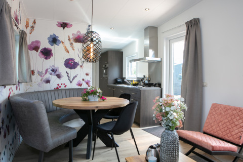 Forest Lodge tiny house bij Holiday Park 't Rheezerwold, gezellige zithoek en moderne bloemenwand.