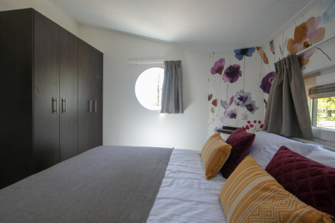 Bedroom in a tiny house at Forest lodge, Holiday Park 't Rheezerwold, Netherlands, modern decor, floral wall.