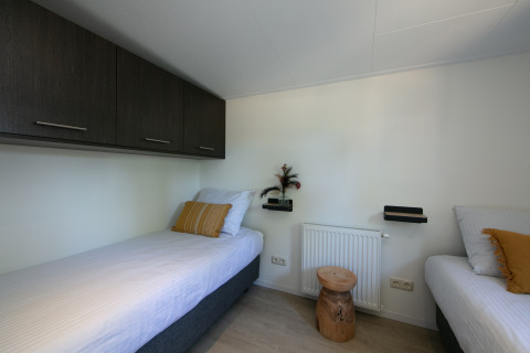 Slaapkamer van Forest Lodge in Holiday Park 't Rheezerwold, Nederland, met twee enkele bedden.