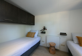 Schlafzimmer der Forest Lodge im Ferienpark 't Rheezerwold, Niederlande, mit zwei Einzelbetten.