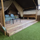 Safari tent with sanitary facilities, wooden deck, seating area and indoor artificial grass display.