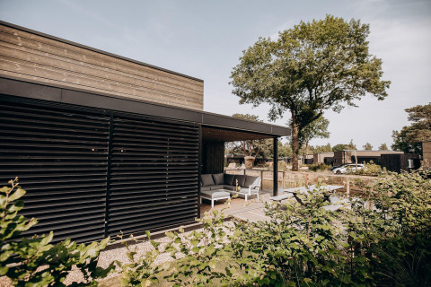 Moderne lodge met terras bij Soof Retreats in Nederland, omgeven door groen en comfortabele zithoek.