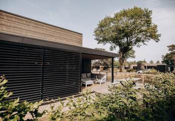Moderne Außenansicht einer Luxury Lodge bei Soof Retreats in den Niederlanden, Terrasse mit Sitzbereich.