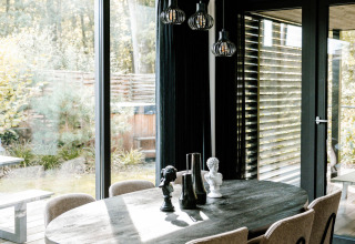 Comedor en una lujosa cabaña de Soof Retreats en Países Bajos con ventanales y decoración moderna.
