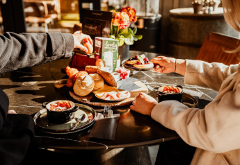 Dos personas disfrutan de un desayuno de lujo con pan, fruta y café en Luxury Family Water Lodge en Países Bajos.