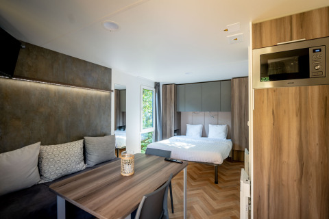 Casa pequeña y moderna en Urban-Gardens, Bélgica, con cama doble, mesa de comedor y una cocina compacta.
