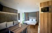 Moderne og kompakt lodge i Urban-Gardens, Belgien, med seng, spisebord og indbygget mikroovn.
