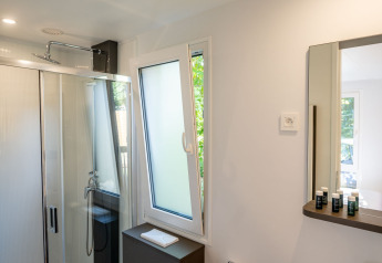 Modern bathroom in a Lodge tiny house at Urban-Gardens, Belgium, featuring a shower, toilet, and sink.