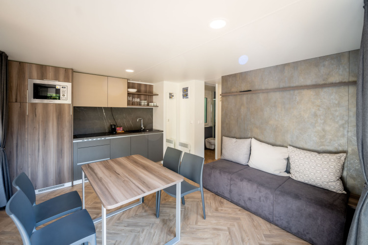 Moderne lodge bij Urban-Gardens in België met open keuken, eethoek en een comfortabele zitbank.