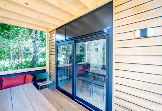 Terras van houten lodge met glazen schuifdeur, zitbanken en uitzicht op groen bij Urban-Gardens, België.