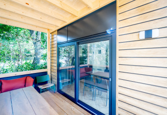 Terrazza in legno con grandi porte a vetro, sedute colorate e vista sul verde a Urban-Gardens, Belgio.