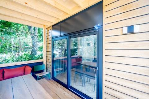 Houten lodge terras met grote glazen deuren, zitgelegenheid buiten en uitzicht op groen, Urban-Gardens, België.