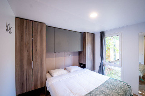 Dormitorio moderno con cama doble, armarios empotrados y ventana grande en Urban-Gardens Lodge, Bélgica.