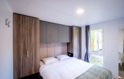 Moderne soveværelse med dobbeltseng, indbyggede skabe og stort vindue i Urban-Gardens Lodge, Belgien.