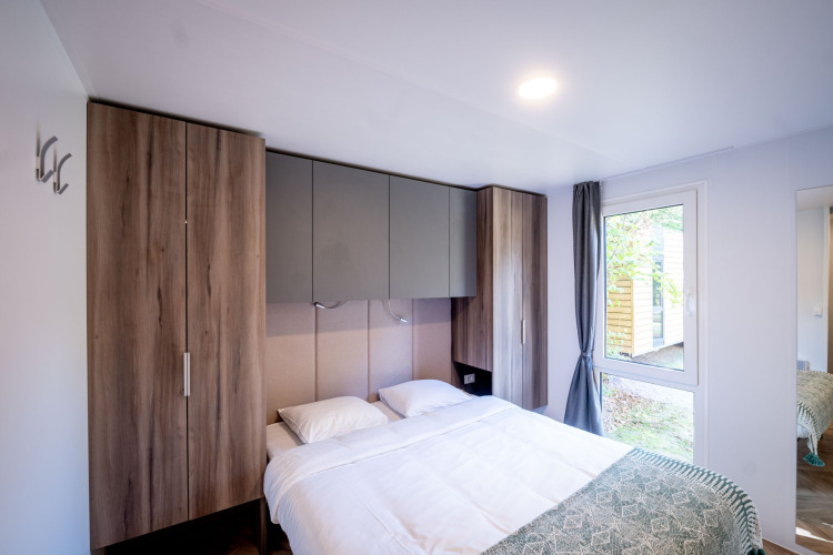 Moderne slaapkamer met tweepersoonsbed, inbouwkasten en groot raam bij Urban-Gardens Lodge in België.