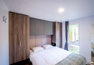 Camera moderna con letto matrimoniale, armadi a muro e grande finestra nella Urban-Gardens Lodge, Belgio.