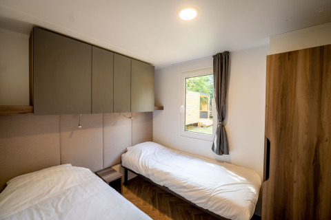 Modernes Lodge-Zimmer im Urban-Gardens Belgien mit zwei Einzelbetten, Schrank und Fensterblick.