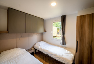 Habitación moderna de la lodge en Urban-Gardens, Bélgica, con dos camas individuales, armario y ventana.